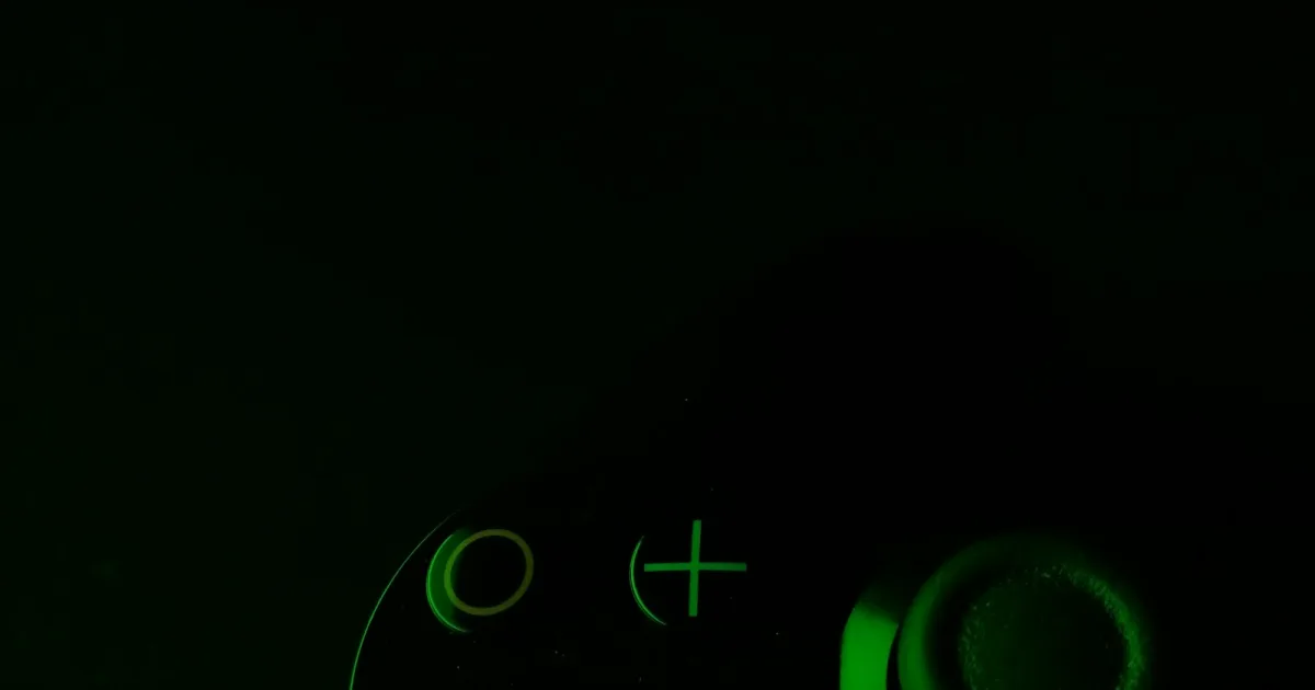 Green-lit game controller buttons in a dark room