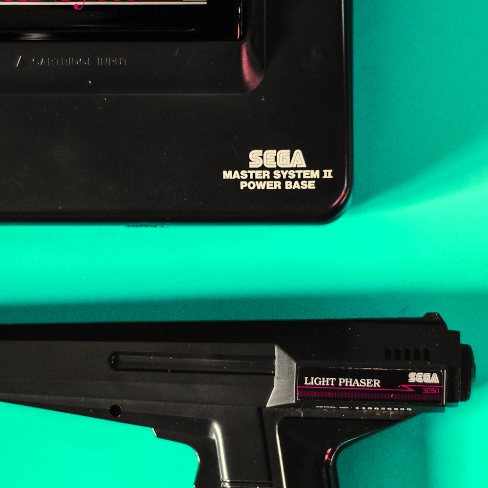 Sega Master System II console nameplate beside its original Light Phaser light gun